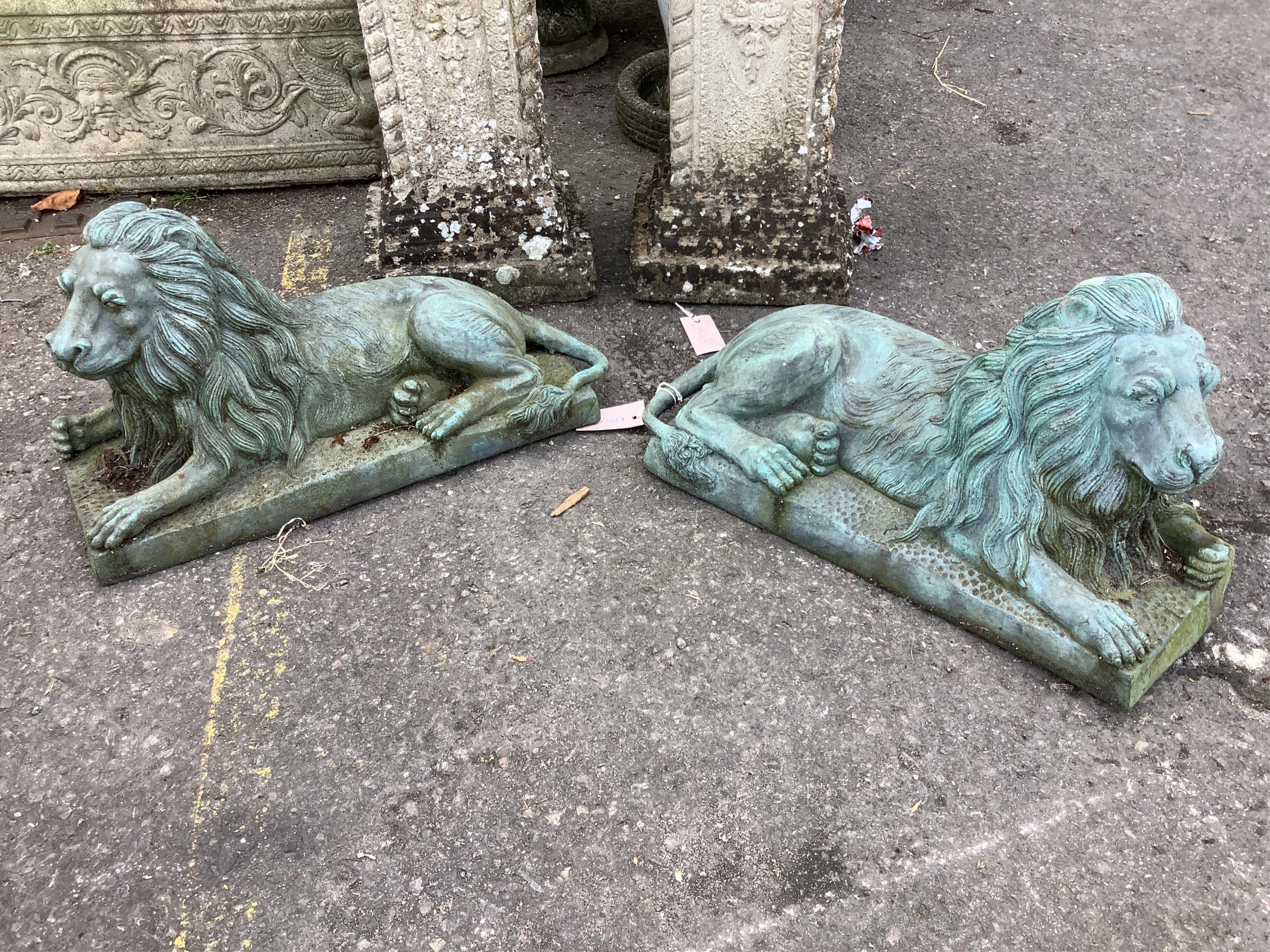 A pair of green patinated cast iron recumbent lions, length 46cm, height 24cm